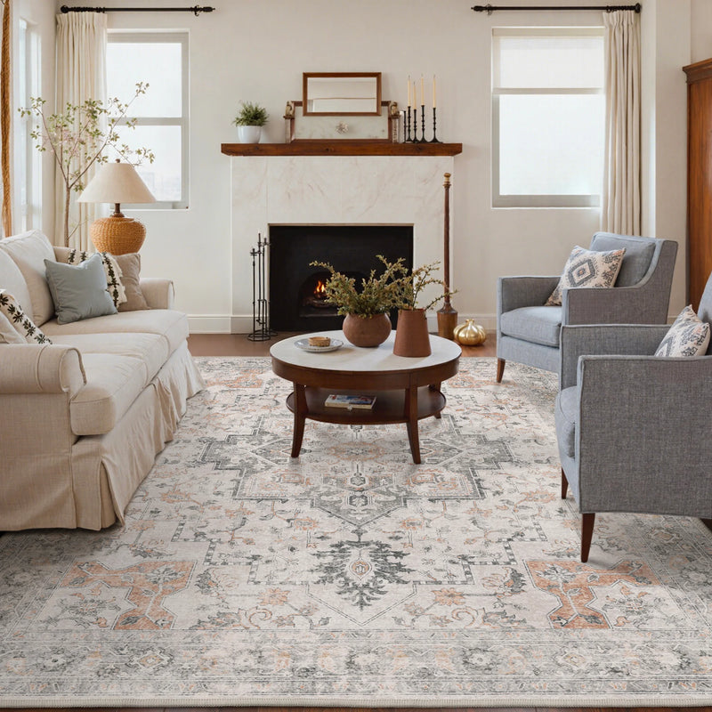 Daria Machine Washable Rugs Non Slip in a living room with cream and gray sofas, round wood table, and fireplace