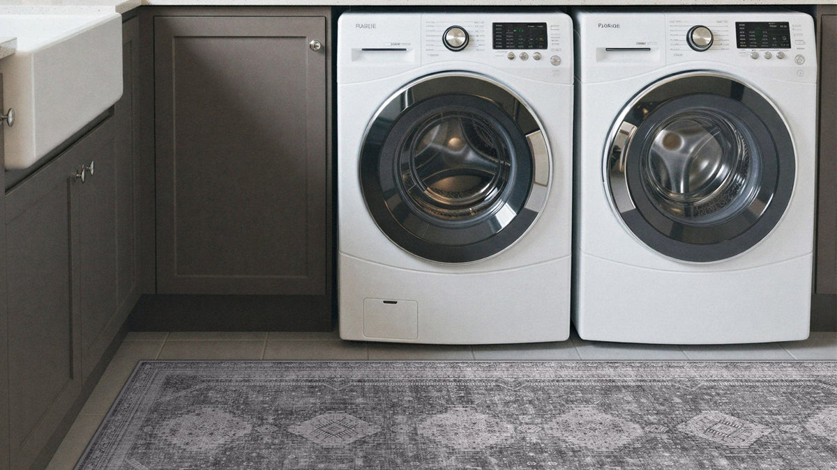 Gray vintage washable rug on a laundry room floor in front of a washer and dryer