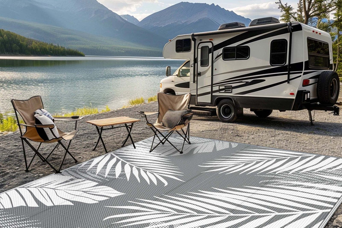 Palma Modern Leaf Reversible Outdoor Rug in gray and white on gravel at a lakeside campsite with an RV and camp chairs